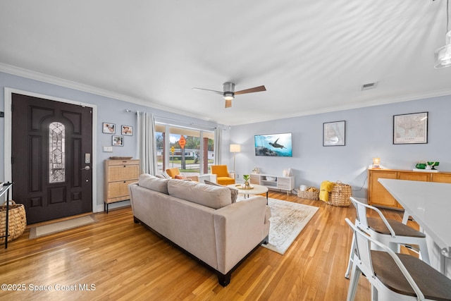 living room featuring crown molding, ceiling fan, and light wood-type flooring