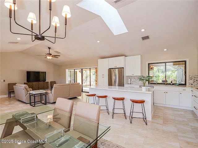 dining space with ceiling fan and lofted ceiling with skylight