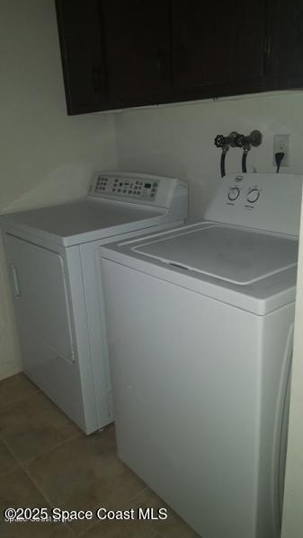 laundry area featuring light tile patterned flooring, cabinets, and separate washer and dryer