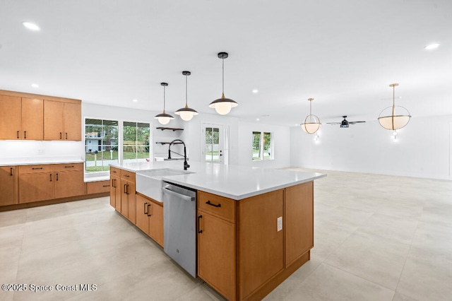 kitchen with sink, hanging light fixtures, stainless steel dishwasher, ceiling fan, and a center island with sink