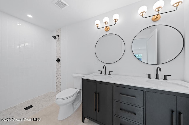 bathroom with tiled shower, vanity, toilet, and tile patterned flooring