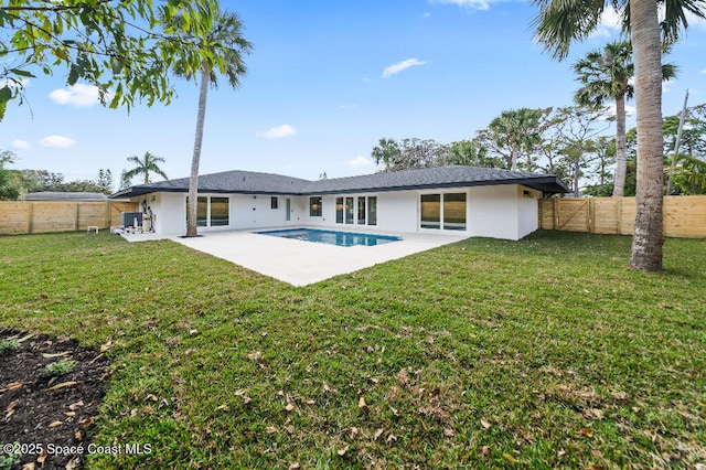 rear view of property featuring a fenced in pool, a patio, and a lawn