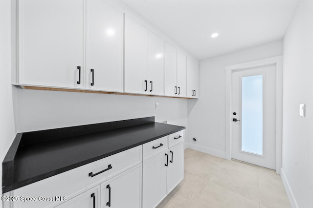 clothes washing area featuring cabinets and light tile patterned flooring