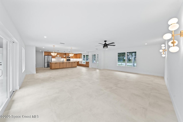 unfurnished living room with ceiling fan with notable chandelier