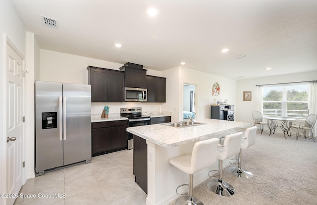 kitchen featuring light tile patterned flooring, a breakfast bar, sink, a center island with sink, and appliances with stainless steel finishes