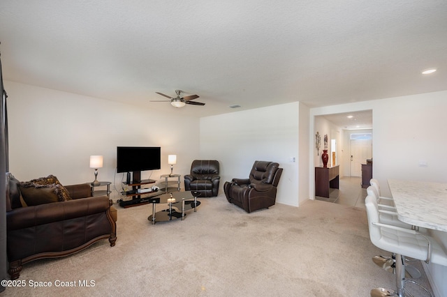 carpeted living room with a textured ceiling and ceiling fan