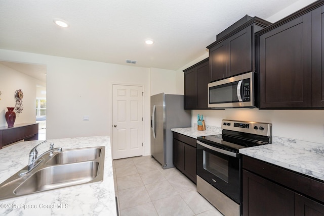 kitchen featuring dark brown cabinetry, stainless steel appliances, sink, and light tile patterned floors