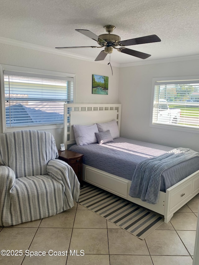 bedroom featuring multiple windows, light tile patterned floors, ornamental molding, and a textured ceiling