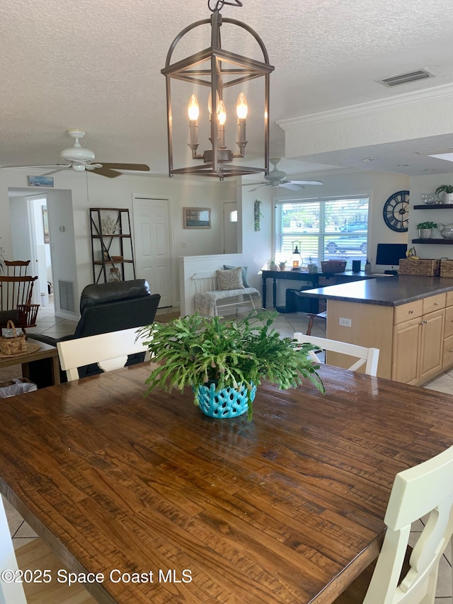 dining space featuring ceiling fan, crown molding, and a textured ceiling