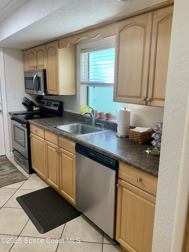 kitchen with light tile patterned flooring, sink, a textured ceiling, light brown cabinets, and appliances with stainless steel finishes