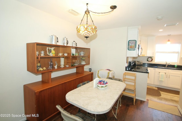 dining room featuring sink, dark wood-type flooring, and an inviting chandelier