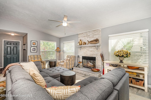 living room with a stone fireplace, a textured ceiling, lofted ceiling, and ceiling fan