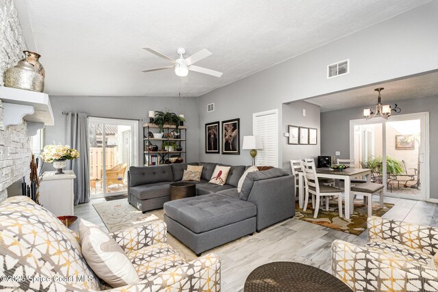 living room with lofted ceiling, ceiling fan with notable chandelier, a textured ceiling, and light wood-type flooring