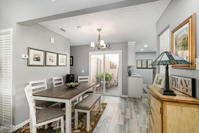 dining space with an inviting chandelier, light hardwood / wood-style flooring, and a textured ceiling