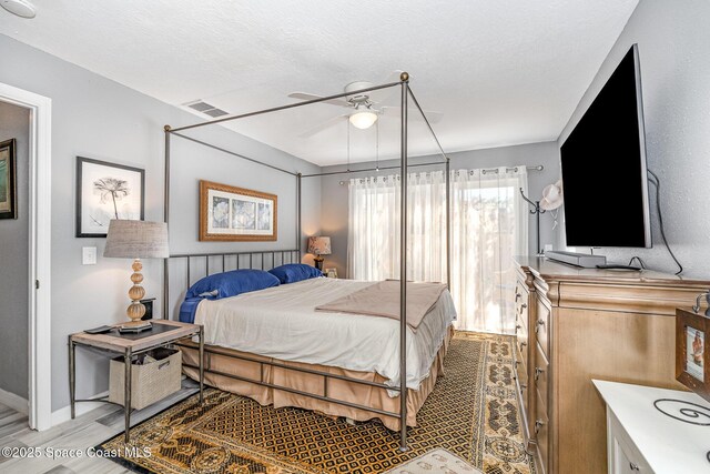 bedroom featuring ceiling fan, light hardwood / wood-style floors, and a textured ceiling