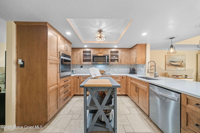 kitchen featuring sink, decorative light fixtures, appliances with stainless steel finishes, a raised ceiling, and kitchen peninsula