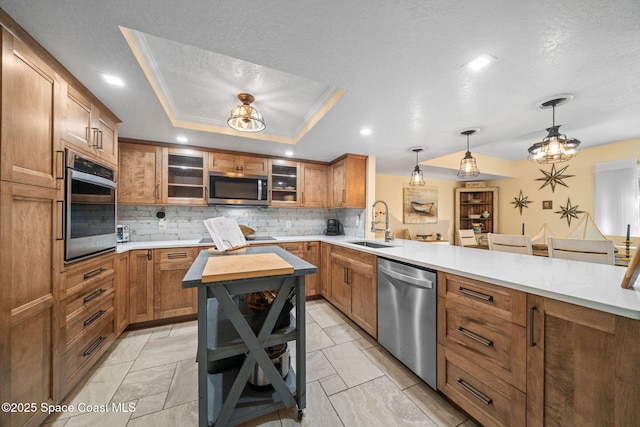 kitchen featuring appliances with stainless steel finishes, a tray ceiling, a breakfast bar area, and hanging light fixtures