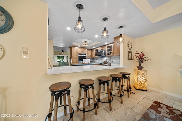 kitchen with appliances with stainless steel finishes, a breakfast bar, decorative backsplash, and kitchen peninsula