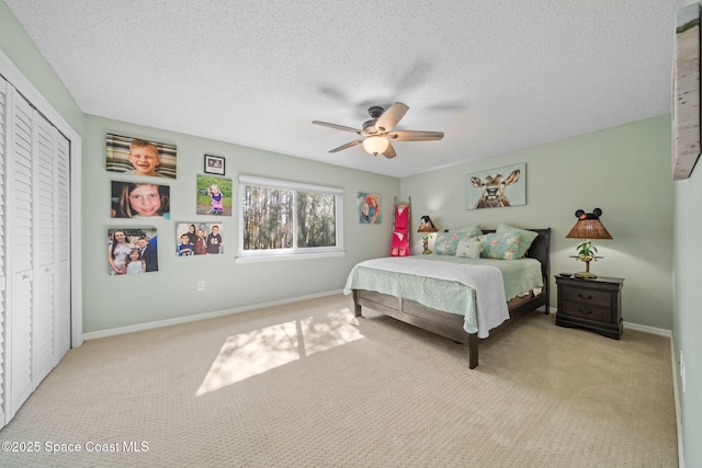 carpeted bedroom featuring ceiling fan, a closet, and a textured ceiling