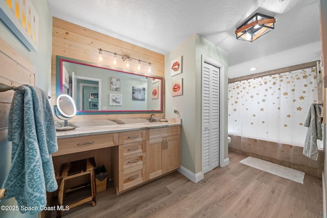 bathroom featuring vanity, hardwood / wood-style floors, wooden walls, and a textured ceiling