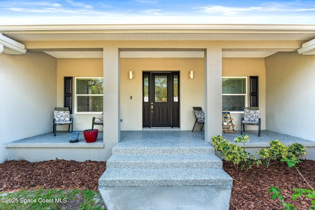 view of exterior entry featuring covered porch