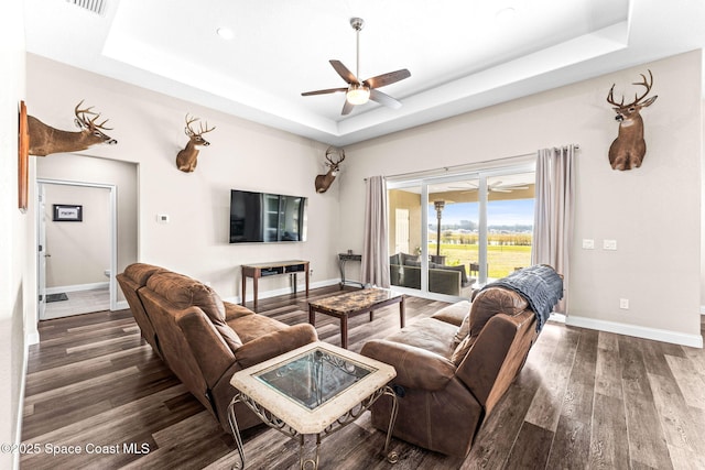 living room featuring a tray ceiling, dark hardwood / wood-style floors, and ceiling fan