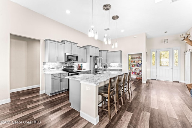 kitchen featuring pendant lighting, a center island with sink, a kitchen breakfast bar, and appliances with stainless steel finishes