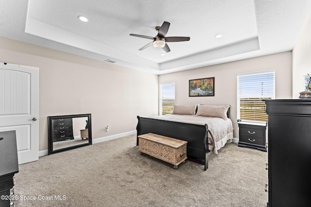 bedroom with a raised ceiling, ceiling fan, carpet flooring, and a textured ceiling