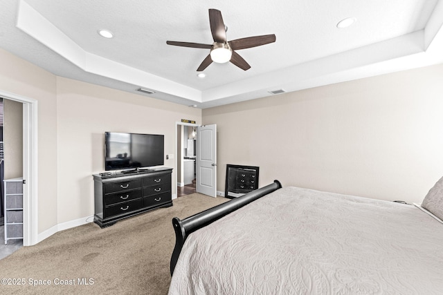 bedroom featuring light carpet, a tray ceiling, and ceiling fan