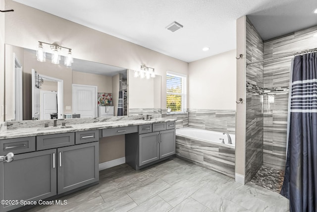 bathroom featuring vanity, plus walk in shower, and a textured ceiling