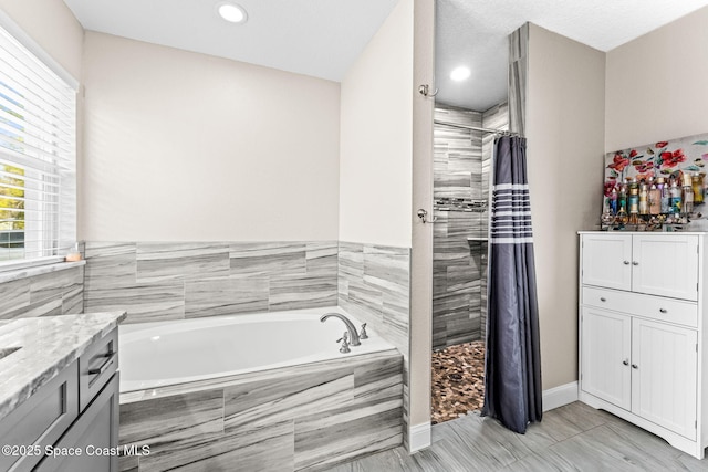 bathroom featuring vanity, independent shower and bath, and a healthy amount of sunlight