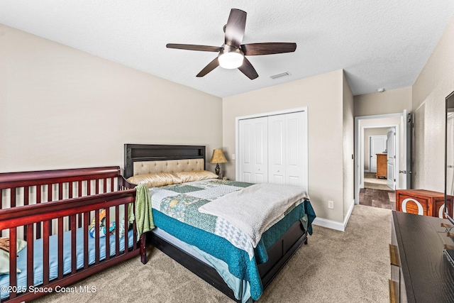 bedroom featuring ceiling fan, light colored carpet, a textured ceiling, and a closet