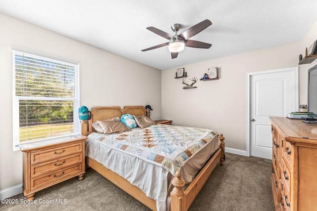 bedroom with a textured ceiling, ceiling fan, and dark colored carpet