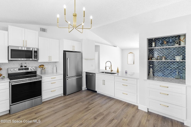 kitchen featuring lofted ceiling, sink, appliances with stainless steel finishes, light hardwood / wood-style floors, and white cabinets