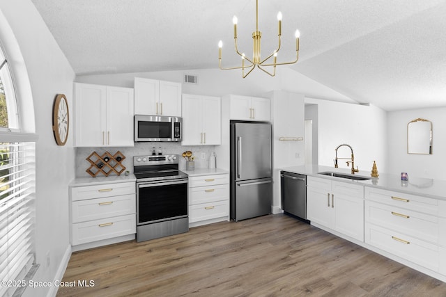 kitchen featuring sink, decorative light fixtures, appliances with stainless steel finishes, hardwood / wood-style floors, and white cabinets