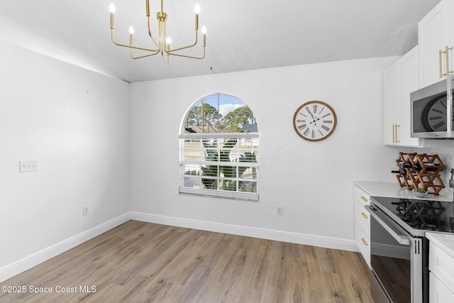 unfurnished dining area with light hardwood / wood-style flooring, a chandelier, and a textured ceiling