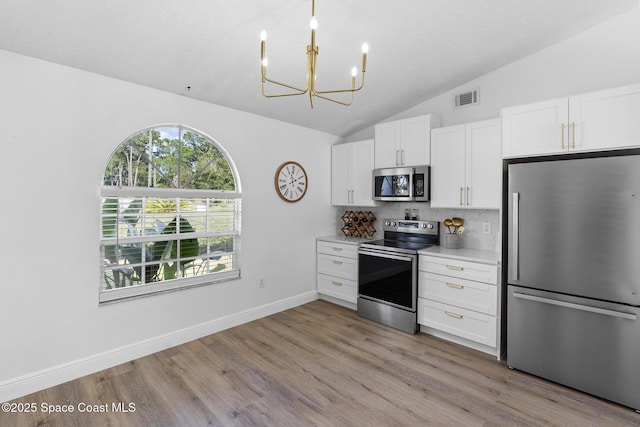 kitchen with white cabinetry, lofted ceiling, stainless steel appliances, and light hardwood / wood-style floors