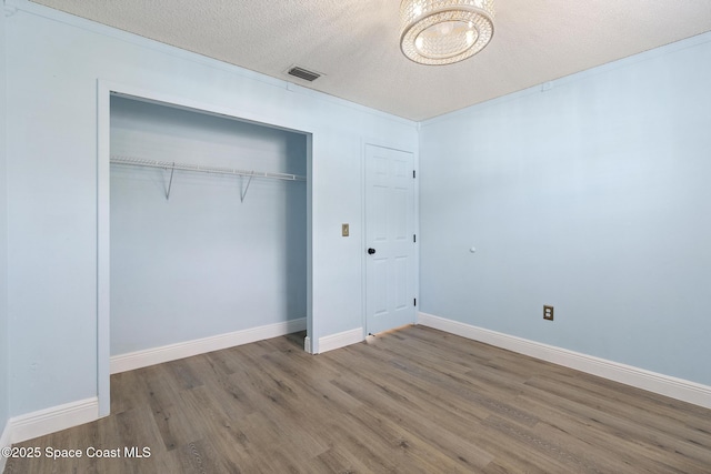 unfurnished bedroom with wood-type flooring, a closet, and a textured ceiling