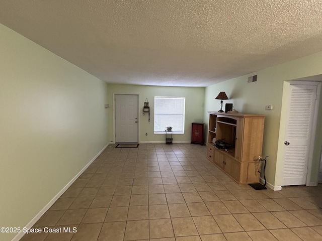 unfurnished living room featuring light tile patterned floors and a textured ceiling