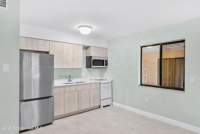 kitchen featuring stainless steel appliances, sink, and light brown cabinetry