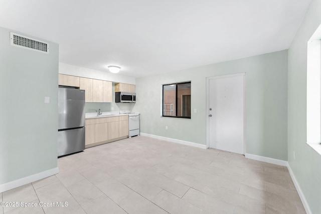 kitchen featuring appliances with stainless steel finishes, sink, and light brown cabinetry