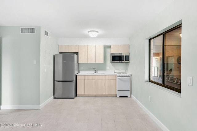 kitchen featuring appliances with stainless steel finishes, light brown cabinetry, and sink