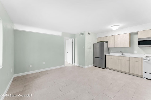 kitchen featuring appliances with stainless steel finishes, light brown cabinetry, and sink