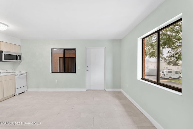 interior space with white range with electric cooktop and light brown cabinetry