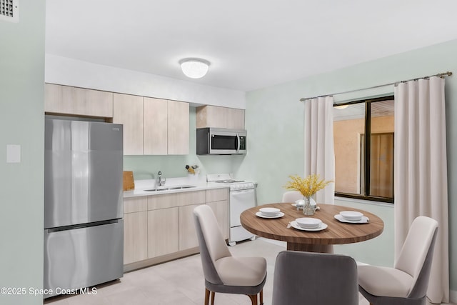 kitchen featuring stainless steel appliances, sink, and light brown cabinetry