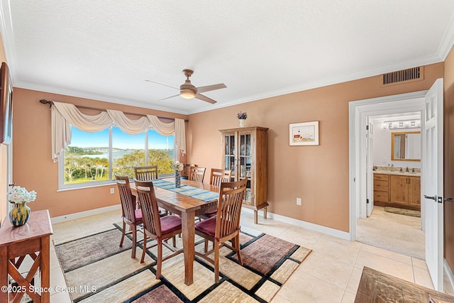 tiled dining space with ornamental molding, ceiling fan, and a textured ceiling