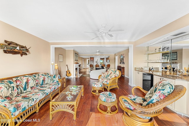 living room featuring wine cooler, crown molding, indoor wet bar, dark hardwood / wood-style flooring, and ceiling fan