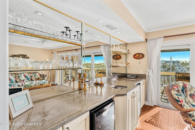 kitchen with light hardwood / wood-style floors, ornamental molding, beverage cooler, and a healthy amount of sunlight