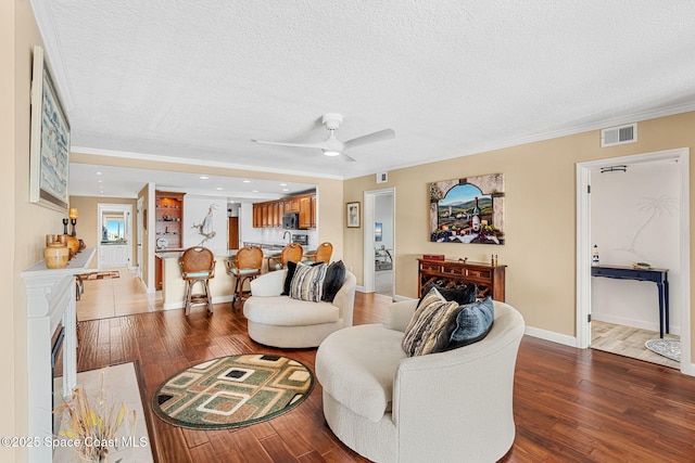 living room featuring ornamental molding, a textured ceiling, and light hardwood / wood-style floors