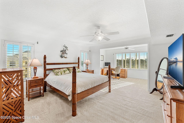 carpeted bedroom featuring multiple windows, ceiling fan, and a textured ceiling